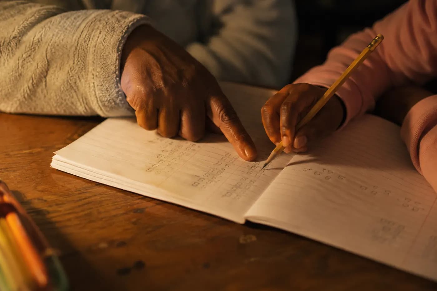 An adult hand and a child's hand on an open exercise book