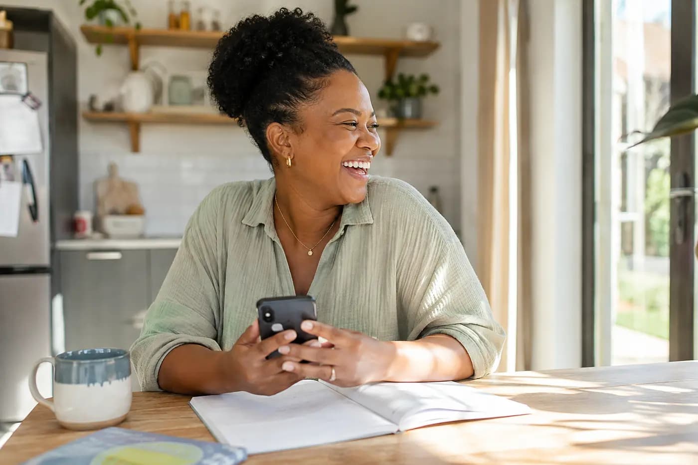 A mother laughing at the kitchen table after reading a coaching card